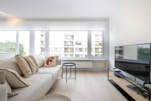 a living room with a white couch and a tv at Trendy 1 bedroom flat near Schuman and Berlaymont in Brussels