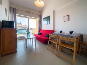 a living room with a red couch and a table at Apartment Les Flots Bleus by Interhome in Le Barcarès