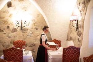 een vrouw in een eetkamer met tafels bij Hotel Castel Rundegg (Adults Only) in Merano