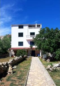a white building with a pathway in front of it at Family Apartment Miluna in Metajna