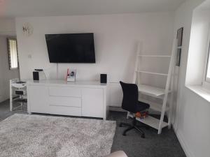 a room with a white desk with a television and a chair at Hawarden near Chester in Hawarden