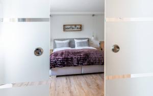a bedroom with a bed with white walls and wooden floors at Ferienwohnung "Hirschbergsuite" - Mit Hotelfrühstück, Sauna, fast direkt am See in Schliersee