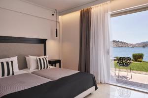 ein Schlafzimmer mit einem Bett und einem großen Fenster in der Unterkunft Xenia Poros Image Hotel in Poros