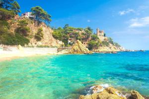 vistas a una playa con un castillo en una colina en Solàrium con terraza a 5 minutos de la playa, en Girona