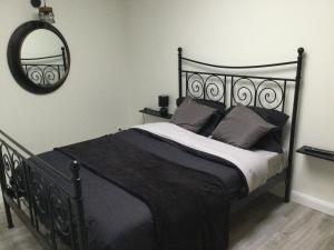 een slaapkamer met een zwart bed en een spiegel bij La Petite Allée in Wimereux