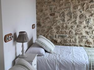 - une chambre avec un lit et un mur en pierre dans l'établissement Casa El PIORNO, à Noriega
