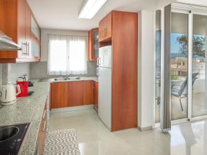 cocina con armarios de madera y nevera blanca en Apartment Misefo - PIC275 by Interhome, en Son Serra de Marina