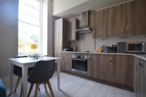 a kitchen with wooden cabinets and a table and a table and chairs at Beautiful flat in luxury Graylingwell development in Chichester