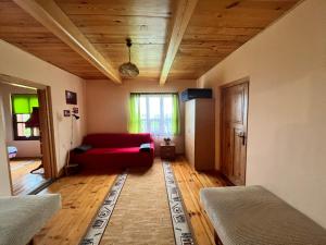 salon z czerwoną kanapą i drewnianym sufitem w obiekcie Świętokrzyska Chata Biegacza w mieście Nowa Słupia