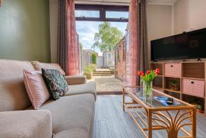 a living room with a couch and a tv and a table at Close to A46 City Centre Sleeps 6, 5 Beds Ensuite FREE Wi-Fi Queens House Inspire Homes in Parkside