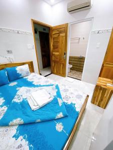 a bedroom with a blue bed and a bathroom at Hotel thanh vinh in Ho Chi Minh City