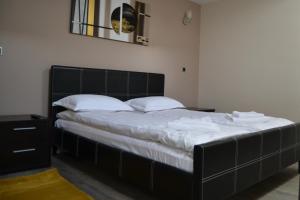a bedroom with a large black bed with white sheets at Tomy Apartment Silver Mountain in Poiana Brasov