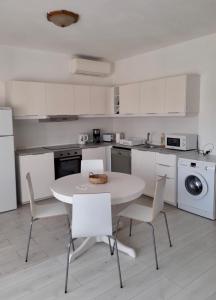a white kitchen with a white table and chairs at Belamandil Garden ,family holidays ,caminho do torrejao olhao in Olhão +25 photos