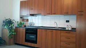 a kitchen with wooden cabinets and a black stove top oven at Casa Vacanze Hartriegel in Comano Terme
