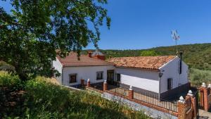 a white house with a fence and a hill at Complejo Residencial Barquero Pernía Cañete la Real by Ruralidays in Cañete la Real
