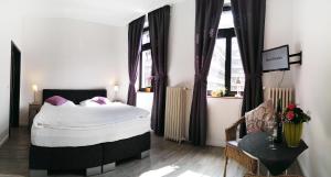 a bedroom with a large bed and two windows at Hotel Klenkes am Bahnhof in Aachen