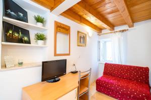 um quarto com uma secretária, uma televisão e um sofá vermelho em Foteza Apartments em Dubrovnik