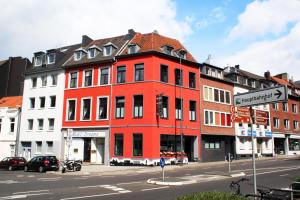 a red building on the corner of a street at Hotel Klenkes am Bahnhof in Aachen