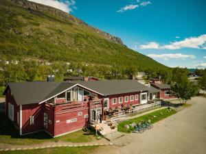 une maison rouge avec une montagne en arrière-plan dans l'établissement Kilpisjärven Retkeilykeskus Cottages, à Kilpisjärvi