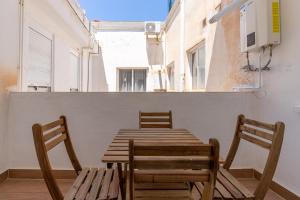 2 sillas, mesa de madera y sillas en el balcón en HOMEABOUT LA MERCED Apartments en Málaga