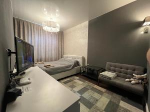 Habitación con escritorio, TV y sofá. en Kingsize bed Self check in & Smart tv and Parking, en Riga