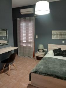 a bedroom with a bed and a desk and a fan at Avra Rooms in Ermoupoli +32 photos