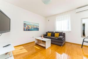 a living room with a couch and a tv at Summer Breeze Pool Apartments in Novalja