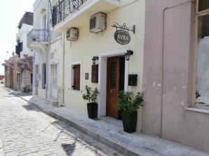 a street in a town with potted plants in front of a building at Avra Rooms in Ermoupoli +32 photos
