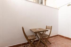 a table and two chairs next to a white wall at HOMEABOUT LA MERCED Studios in Málaga