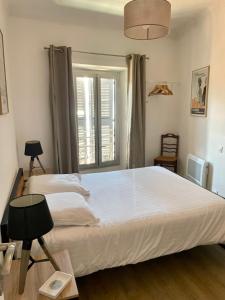 a bedroom with a large white bed and a window at Joli appartement à côté du Palais des Festivals in Cannes
