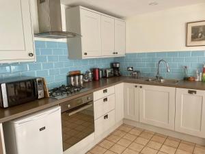 a kitchen with white cabinets and a stove top oven at Windsor View in Hebden Bridge