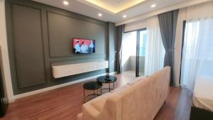 クイニョンにあるFLC Sea Tower Quy Nhơn - Kadupul Homeのソファと壁掛けテレビのあるリビングルーム