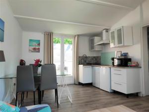 una cocina con armarios blancos y una mesa con sillas. en Maison T2 proche mer jardin spa jacuzzi et parking en Six-Fours-les-Plages
