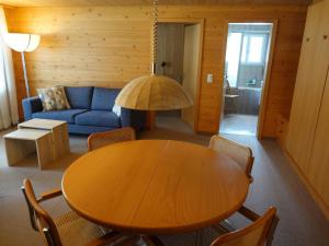 sala de estar con mesa de madera y sofá azul en Apartment Kronenplatz 6 # 2 by Interhome, en Lenk