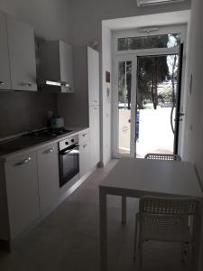 una cocina con armarios blancos y una mesa con sillas. en B&B Lido Apartament 10B, en Civitanova Marche
