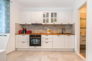 a kitchen with white cabinets and a black oven at House Tia in Vrboska