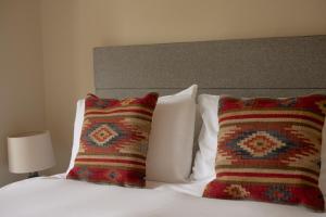 a bedroom with a bed with two pillows and a headboard at The Grosvenor Arms in Hindon