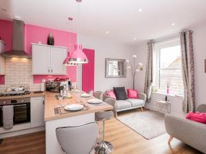 a kitchen and living room with pink walls at Gull Cottage in Dartmouth