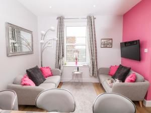 a living room with two couches and pink walls at Gull Cottage in Dartmouth