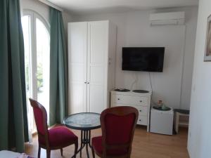 uma sala de estar com uma mesa e cadeiras e uma televisão em Ana Rooms em Krk