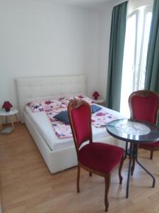 a bedroom with a bed and two chairs and a table at Ana Rooms in Krk