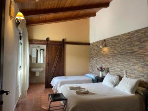 a bedroom with two beds and a brick wall at FINCA LAS DEHESILLAS in Monesterio