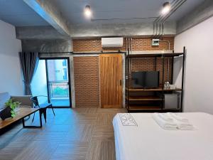 a room with a bed and a tv and a couch at Loft 202 Hotel in Bangkok