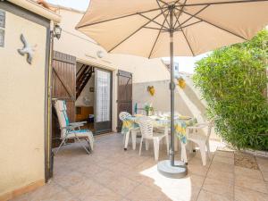 een patio met een tafel en stoelen en een parasol bij Holiday Home Les Maisons de la Plage-1 by Interhome in Le Grau-du-Roi