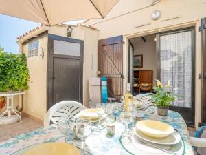 - une table avec des assiettes et des verres sur la terrasse dans l'établissement Holiday Home Les Maisons de la Plage-1 by Interhome, au Grau-du-Roi