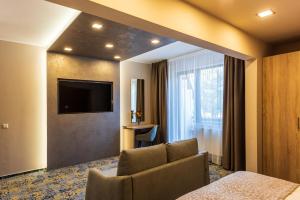 Hotel Tusnad في بايلي توشناد: غرفه فندقيه مع اريكه وتلفزيون