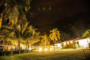 un complejo nocturno con palmeras y luces en Corsário Hotel, en Ubatuba
