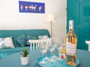 ラ・グランド・モットにあるHoliday Home Villas Plein Soleil 1 by Interhomeのワイングラス付きのテーブルに座ったワイン1本