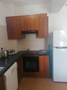 cocina con armarios de madera y nevera blanca en Spacious 3 bedroom villa private pool en Pafos