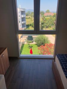 uma mulher num vestido vermelho a olhar pela janela em Bashi's Apartments em Donji Štoj